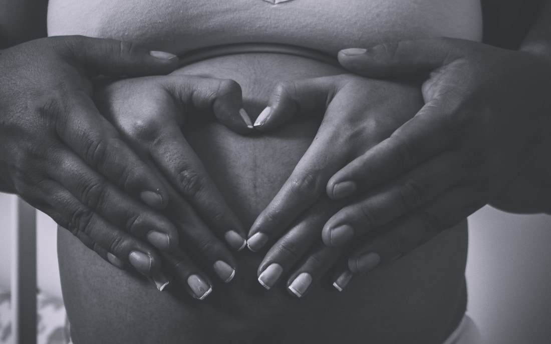 Image of two sets of hands on a pregnant belly