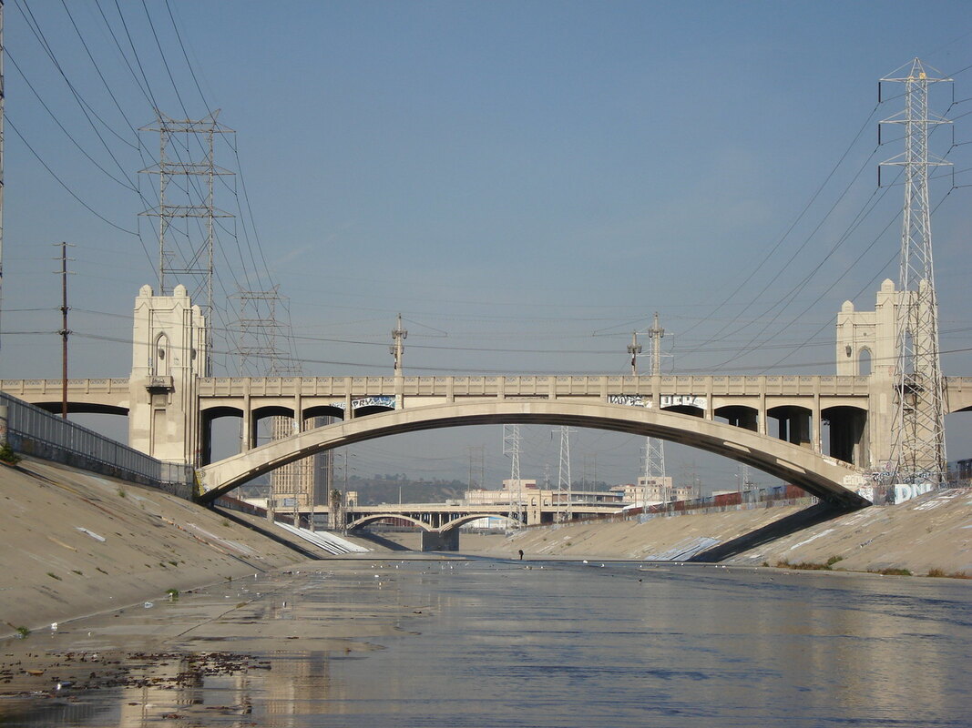 Image of the Los Angeles River with concrete embankments and a bridge over the ravine.