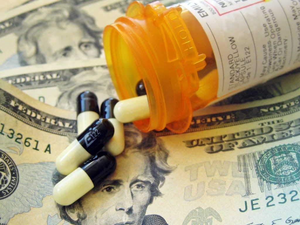 Image of pills and pill bottle on USD $20 bills