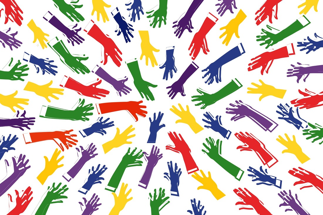 Image of multi-colored hands reaching to a center focal point