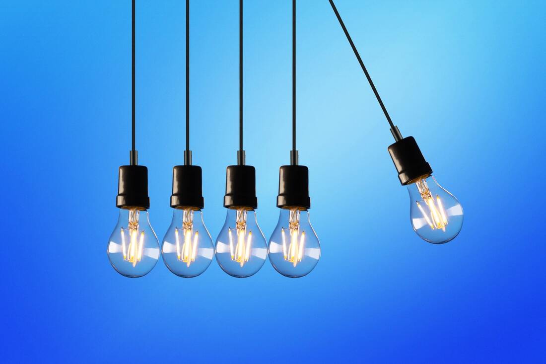 Picture of five lightbulbs hanging from wires in a line. One is elevated and about to swing into the next bulb.