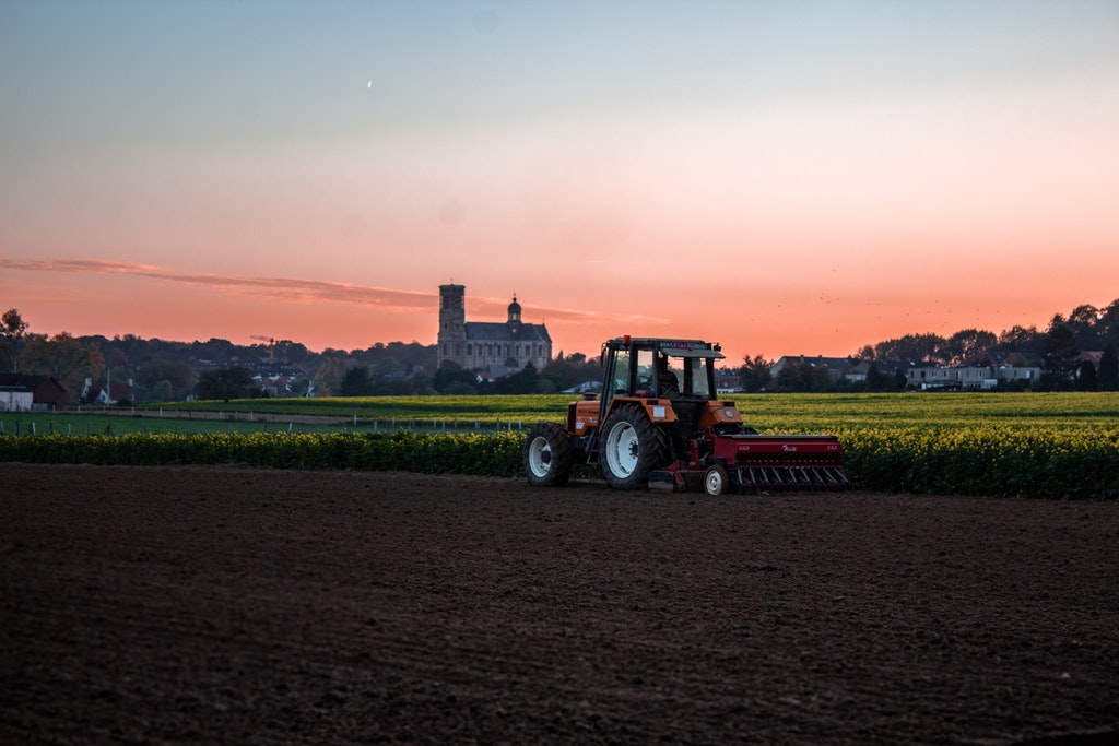 Image of a tractor harvesting crops at dusk